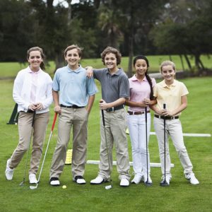 Group of children (10-14 years) on golf driving range, taking golf clinic.